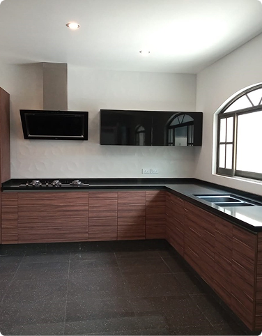 Cocina de madera con cubierta negra y ventana arqueada